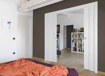 Vier Türblätter aus Holz in einem Eclisse TELESKOP Einbaukasten für in der Wand laufende Schiebetüren. Installiert in einer Trockbauwand im Schlafbereich.
